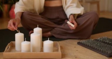 Kibrit yakan genç bir kadın, aromatik mumlar, yakın çekim yavaş çekim, yaşam tarzı, meditasyona hazırlık, yoga pratiğiyle aromaterapi. Formda kız evde mum yakıyor. Rahatlama dinlenmesi