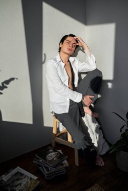 Zarif genç düşünceli adam alnına dokunuyor, sandalyeye oturuyor, plan yapıyor, kenar manzaralı tam boy portre, boş zaman, boş zaman, yaşam tarzı