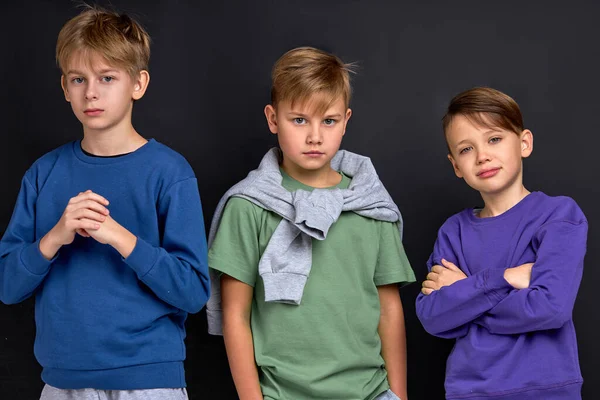 self assured children in casual stylish clothes looking at camera against black background gang is ready to fight with opponents