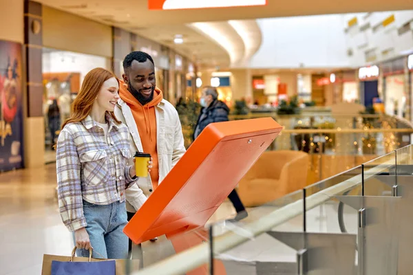 快乐快乐的多元家庭在购物中心的信息亭作为互动的客户服务 夫妻在超级市场购物时使用导航器 侧视图照片 — 图库照片