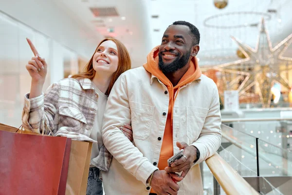 Gülümseyen Kızıl Kız Mağazayı Işaret Ediyor Giysiler Alışveriş Merkezinde Erkek — Stok fotoğraf