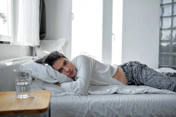 Jonge Knappe Serieuze Man Kijkt Naar Camera Liggend Het Bed — Stockfoto