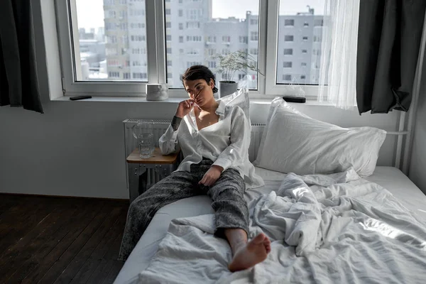 Handsome slim depressed man wants to smoke cigarette lying on his bed. caucasian guy wants to lighting cigar.full length photo, addiction depression