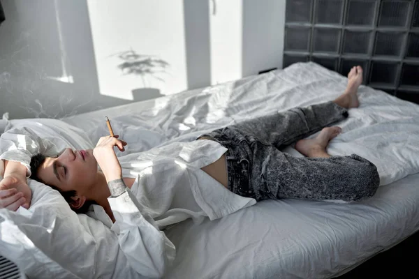 目を閉じた男が寝室に寝そべってる 全長側のビューショット タバコへの影響 — ストック写真