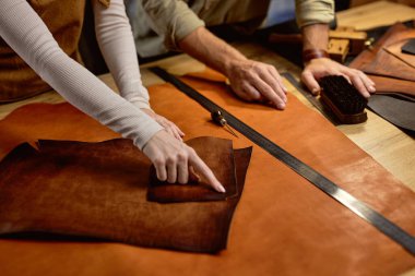 Bir parça doğal deri üzerinde parmağı olan kadın, zanaatkar, materyalin kalitesini, kalınlığını gösterir. Çalışma süreci, eğitim. Kırpılmış vuruşu kapat