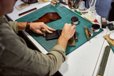 Profesyonel bir zanaatkar eski bir deri cüzdanı yeni gösterir, gerçek bir deri cüzdanı temizler, yakın çekim yapar. renklendirme