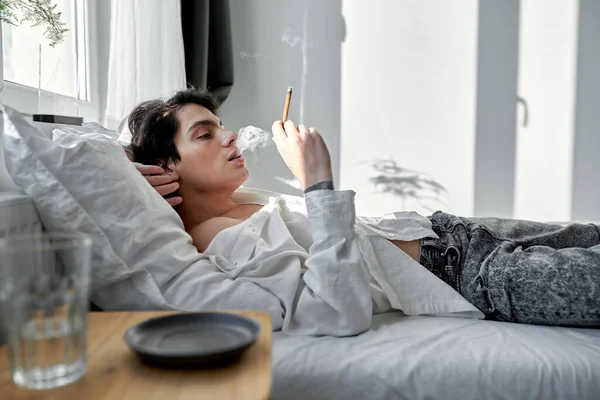 의학적 카나비와 둔기를 피우는 잘생긴 흡연자는 침실에서 시간을 보낸다 내용은 — 스톡 사진