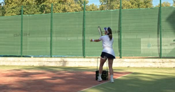 バスケットからボールを取って ジャンプし テニスラケットで強いショットを作るスポーティセクシーな女の子 アウトドアライフスペアタイム — ストック動画