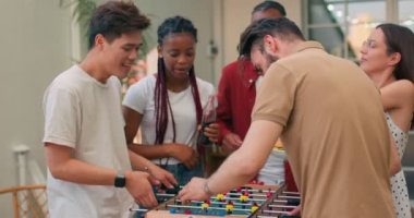 Sakallı adam, yakışıklı Asyalı adam piknikte masa futbolu oynuyorlar. Onlar arkadaşlar. Ağır çekimde meydan okuyun, iş arkadaşları tezahürat yapıyor, doğum gününün tadını çıkarıyorlar.