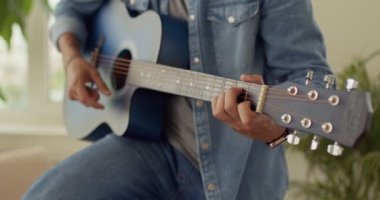 Mavi gömlekli genç adam ışık odasındaki çağdaş elektro gitar grubu provasında akort çalıyor.