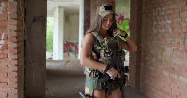 防護服を着たスポーティな女が銃をチェックする ワークアウトの遅い動きで休憩している軍用ギアの疲れている女性 — ストック動画