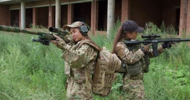 視聴者を狙ったアサルトライフルを持った女性兵士屋外に立ち女性を守り地域を確保地域を監視カメラの動き — ストック動画
