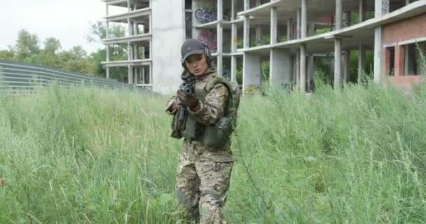 身着迷彩服的女兵走在高高的草地上 瞄准猎枪 女孩与朋友打打斗 寻找对手 慢动作 — 图库视频影像