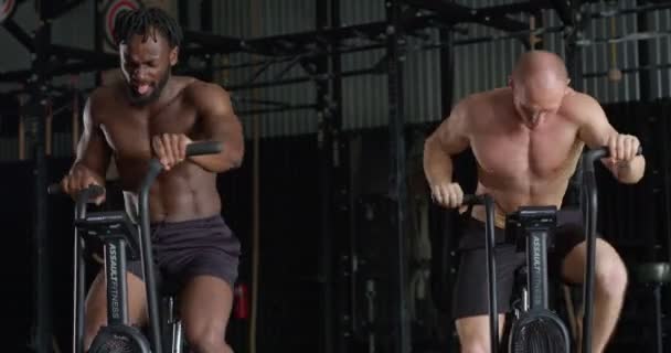 有野心的两个不同的男人旋转着空气自行车 空中自行车和有氧运动训练 用于运动 锻炼和强壮的身体 肌肉和力量的锻炼 — 图库视频影像