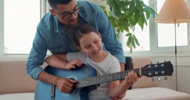 Yetenekli özel öğretmen küçük öğrencisine gitar çalmada iyi olmayı öğretiyor. Öğretmenler ders sırasında tecrübelerini ve becerilerini paylaşıyor. yavaş çekim
