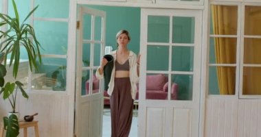 Güzel, gülümseyen bir kız kapıyı açıyor, yanında duruyor, kameraya bakıyor, sabahına yoga egzersizleriyle başlıyor. Günaydın, kadın elinde hasırla evde yürüyor, günlük ruitine kamera hareketi.