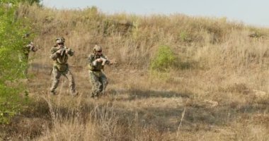 Askerler hedefe ulaşıyor, dizlerinin üzerinde oturuyor, ağır çekimde çekim yapmaya hazırlanıyor, askerlerin güvenliği sağlanıyor. Adamlar kurbanların kafalarına nişan alıyor..