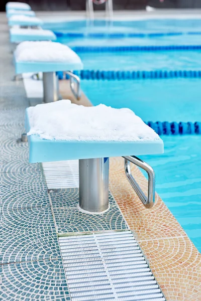 snowy springboard in the pool outdoors, equipment for swimmers. empty swimming pool. blurred background