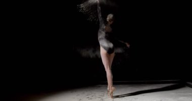 Toz konseptinde dans. Toz içinde güzel beyaz kadın dansçı, siyah tulum giyen, izole edilmiş siyah stüdyo arka planında un bulutu içinde dans eden kadın dansçı. sanat, performans