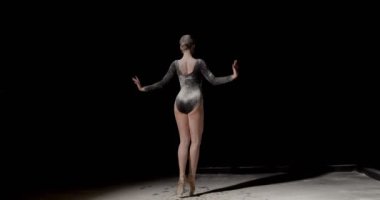 Siyah stüdyo arka planında izole edilmiş un içinde dans eden zarif klasik balerin, girdaplar. Siyah elbiseli ince kadın. Grace, sanatçı, hareket, aksiyon ve hareket konsepti. Ağırlıksız görünüyor..