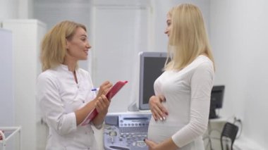 Hamile müşteri stok yapıyor ve hemşireyle konuşuyor. Toplantı, danışma
