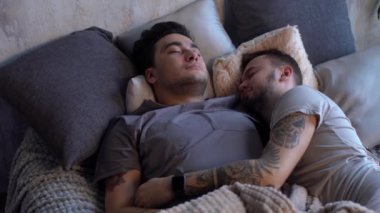 Genç tatlı çift aynı cinsiyetten romantizm yaşıyor, yatakta öpüşüyor, tutkulu aktif adam sevgilisini caddle, balayı, LGBT konseptinde yakalıyor..