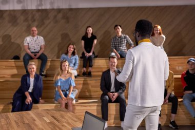 İş toplantısındaki konferans salonunda konuşma yapan Afrikalı erkek konuşmacı. Konferans salonunda ders dinleyen bir grup insan. İşletme ve girişimcilik. Boşluğu kopyala