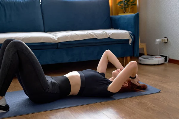 在家里做完健身锻炼 穿着黑色运动服躺在地板上的迷人而又凉爽的女运动员 红头发的高加索女人 过着健康的生活 独自在室内锻炼 — 图库照片