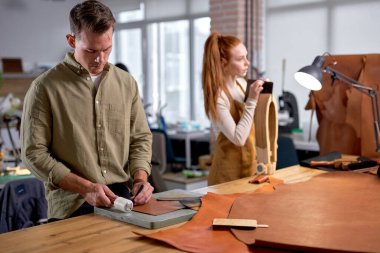 Genç çalışkan insanlar DIY Deri Projeleri 'ne katılıyorlar. Krater masanın arkasında duruyor, işine konsantre oluyor.