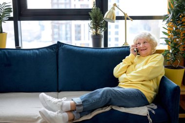 Rahat bir odada kanepede oturan, emekli bir kadın arkadaşlarıyla sohbet ederken telefonda oldukça mutlu bir son sınıf kadını. Kafkasyalı kadın günlük giysiler içinde, yalnız başına dinleniyor.