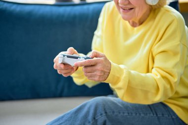 Mutluluktan kırbaçlanmış, kır saçlı, joystick 'li yaşlı kadın boş zamanlarında odada oyun oynuyor, tek başına. Yaşlılar ve modern cihazlar, modern teknoloji kavramı. hafta sonlarında