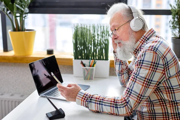 Красивый Пожилой Мужчина Сидящий Один Современным Ноутбуком Наушниками Бородатый Мужчина — стоковое фото