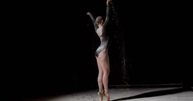 Parmak uçlarında uçlar. Genç zarif balerin tek başına un üzerinde dans ediyor, izole edilmiş siyah bir arka planda. Sanat, hareket, hareket, esneklik, ilham konsepti. Puanlı ayakkabılı klasik balerin.