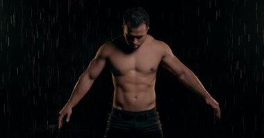 Çıplak gövdeli kaslı bir adam karanlık arka plana bakıyor. - Evet. Kot pantolonlu, memnun sakallı adam yağmurda duruyor. İnsan havadan mutlu olur, insan kollarını yana doğru açar, yana bakar.