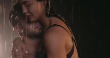 strong bearded man holding sexy lady in black bra, panties, touching her ass, butt, camera motion. fit man, his female lovers enjoying intimacy.Jets of water flow in fast motion over bare nude bodies