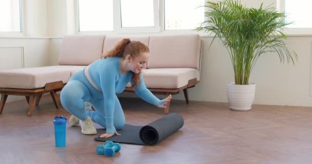 Lustige Mollige Schöne Frau Faltet Schwarze Gymnastikmatte Auf Dem Boden — Stockvideo
