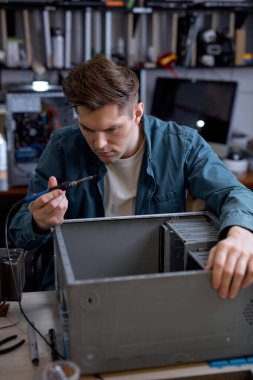 Profesyonel hizmet merkezindeki dizüstü bilgisayarların onarımı ve teşhisi. Genç profesyonel elektronik ustası atölyede masa başında aletlerle oturuyor. bilgisayarlar tamir kavramı