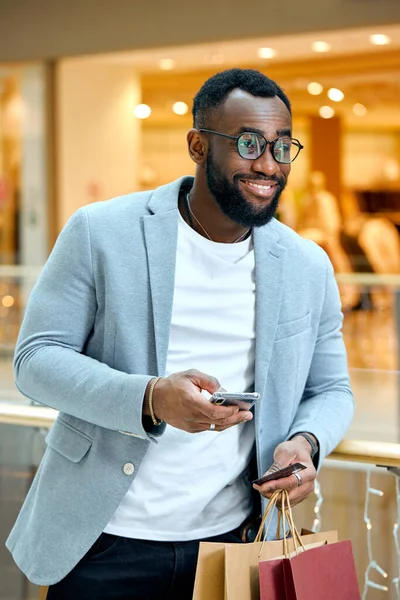 Stock image joyful good-looking smart man in fashion clothes doing online shopping, close up side view photo