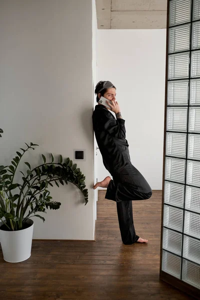 young glamour man with raised leg making a phone call in the morning, full length side view shot, rest, guy makes appointment, meeting with girlriend, boyfriend