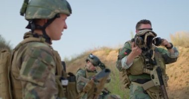 Kamuflajlı yorgun adamlar işten sonra dinleniyorlar. Başarılı bir maçtan sonra sohbet ediyorlar.