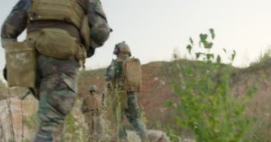 Güçlü askerler tepeye tırmanır. Asker dağlarda yürür, yardım etmek için koşar, arkadaşlarını yavaş çekim kamerayla kurtarır.
