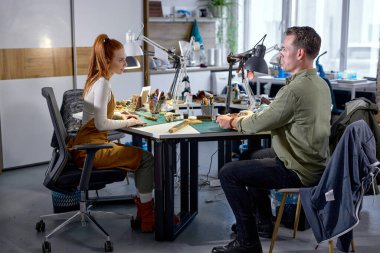 Heyecanlı hevesli gençler el yapımı cüzdanlar, çantalar, saatler ve aksesuarlar yapıyorlar. tam uzunluktaki kenar görüntüsü