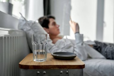 Masadaki cam ve tabağa odaklan. Arka planda sigara içen yakışıklı adam..