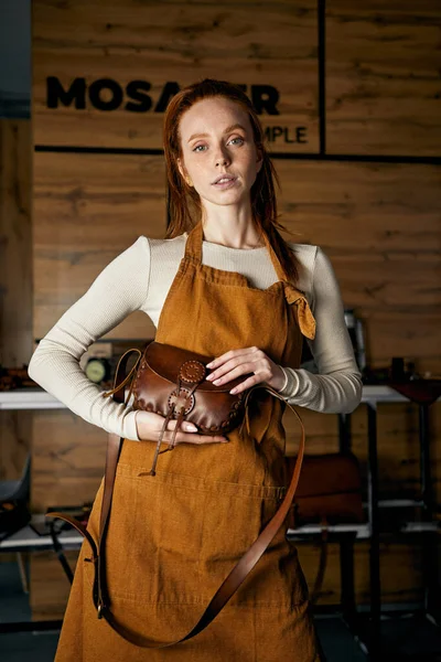 skilled craftswoman shows a master class of sewing bags, wallets, young artisant offer her service.welcome to master class of making leather products