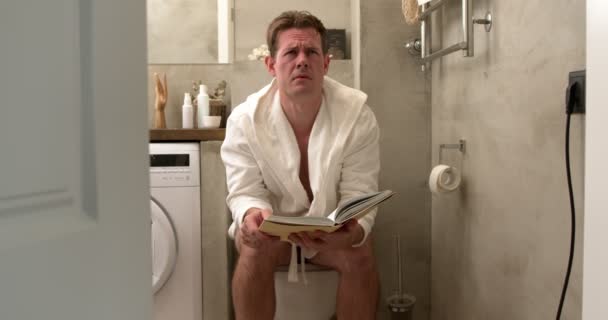 Homem Americano Sentado Banheiro Sentindo Infeliz Contém Livro Diarréia Constipação — Vídeo de Stock