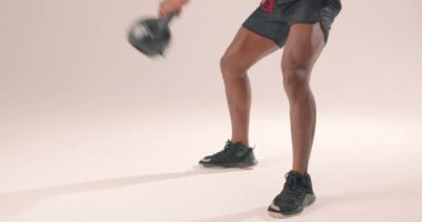 Stüdyoda kettllbell ile antrenman yapan kaslı güçlü siyah adam dayanıklılık eğitimi alan vücut geliştiren adam sağlıklı yaşam ve vücut bakımını ağır çekimde tutuyor.