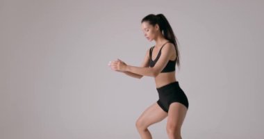 Genç fit esmer, at kuyruklu güzel kız. Stüdyoda spor yapıyor. Evde spor yapıyor. Sağlıklı yaşam tarzı, eğitim, spor, kilo kaybı. Çömelme, kenar görünüm kopyalama alanı