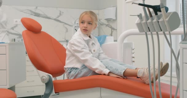 可爱的小女孩在牙医柜里玩得很开心 严重不快乐的小女孩在诊所里有不同的情绪 害怕的孩子害怕医生 牙医钻慢动作的侧视图 — 图库视频影像