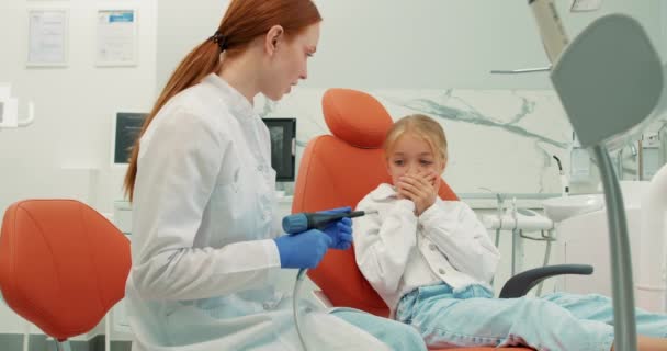 Имбирный Профессиональный Стоматолог Собирается Выполнить Стоматологическую Процедуру Наполнения Испуганного Ребенка — стоковое видео