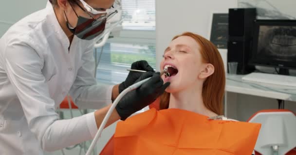 안경을 치과의 여성은 병원에서 머리의 환자의 치아를 치과용 드릴로 치아를 — 비디오